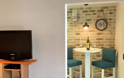 a living room with a tv and a table and a clock at Apartments Maris Garden in Petrovac na Moru