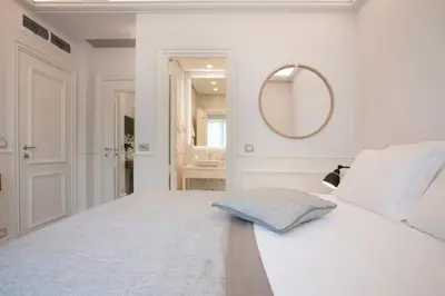 a white bedroom with a bed and a mirror at Hotel Majestic in Budva