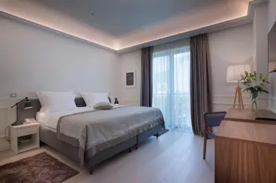a bedroom with a bed and a desk and a window at Hotel Majestic in Budva