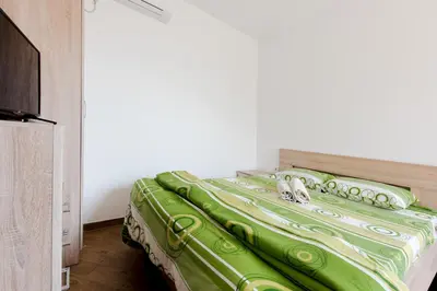 a bed with a green comforter in a room at Apartments Vukmarković in Sutomore