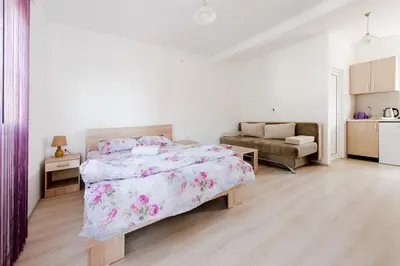 a white bedroom with a bed and a couch at Apartments Vukmarković in Sutomore