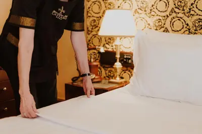 a man making a bed in a hotel room at Historic Boutique Hotel Cattaro in Kotor
