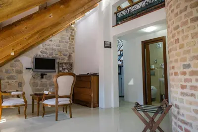 a living room with a tv and a desk and chairs at Hotel Villa Duomo in Kotor