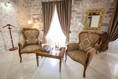 a living room with two chairs and a table and a window at Hotel Villa Duomo in Kotor