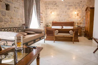 a bedroom with a bed and a couch and a table at Hotel Villa Duomo in Kotor