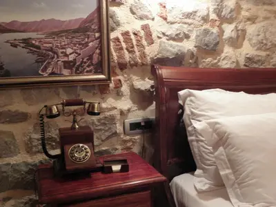a bedroom with a clock on a table next to a bed at Hotel Villa Duomo in Kotor
