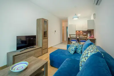 a living room with a blue couch and a table at Adriatic Sunshine Apartment in Budva