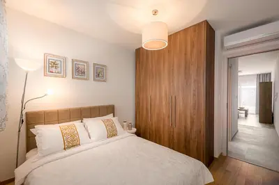 a bedroom with a white bed with a wooden cabinet at Adriatic Sunshine Apartment in Budva