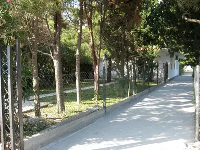 a fence next to a sidewalk with trees at Vila Branka in Čanj