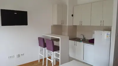 a small kitchen with white cabinets and purple stools at Zebra in Podgorica