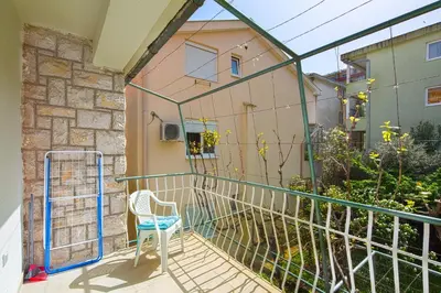 a balcony with a chair and a building at Apartman Aleksandra in Budva