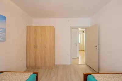 a bedroom with two beds and a wooden cabinet at Apartman Aleksandra in Budva