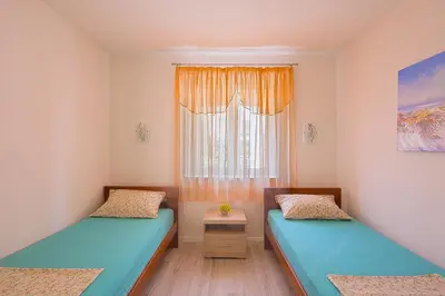 two beds in a small room with a window at Apartman Aleksandra in Budva