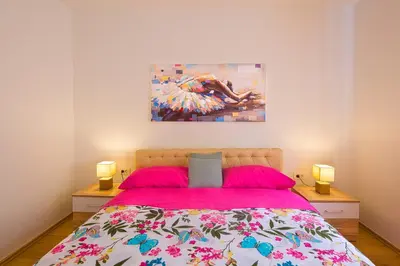 a bedroom with a pink bed with a painting on the wall at Apartman Aleksandra in Budva