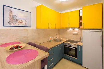 a kitchen with yellow cabinets and a table with a bowl of fruit at Apartman Aleksandra in Budva