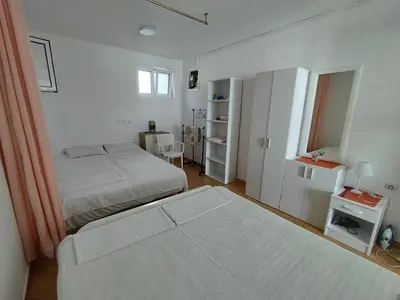 a white bedroom with two beds and a window at Seaside Apartment Kruce in Kruče