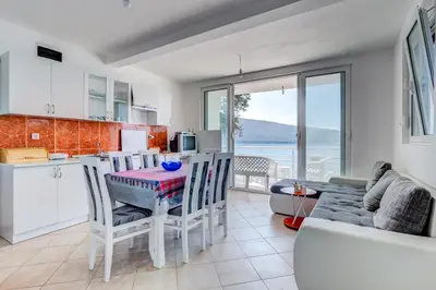 a kitchen and living room with a table and chairs at Seaside Apartment Kruce in Kruče