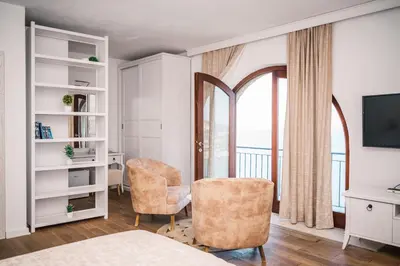 a bedroom with a bed and a chair and a window at Hotel Pirate Old Town in Ulcinj