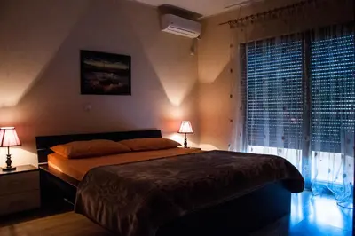 a bedroom with a bed with two lamps and a window at Apartments Rudovic in Ulcinj