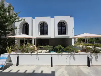a white house with black windows and umbrellas at Marini Casa in Ulcinj