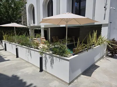a building with a patio with an umbrella and plants at Marini Casa in Ulcinj