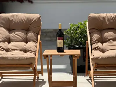 a bottle of wine sitting on a table next to two chairs at Marini Casa in Ulcinj