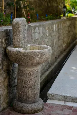 a stone bird bath sitting next to a stone wall at Apartmani Stanisic in Čanj