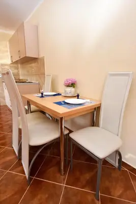 a dining room table with white chairs around it at Apartmani Stanisic in Čanj