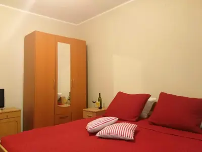 a bedroom with a red bed with two pillows on it at Apartmani Cuce in Kotor