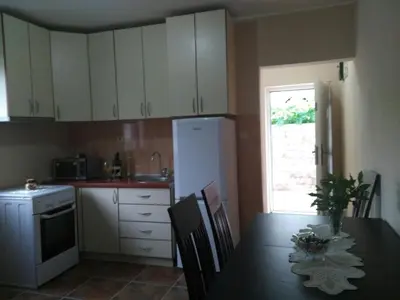 a kitchen with a table and a white refrigerator at Apartmani Cuce in Kotor