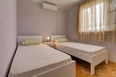 two beds in a small room with a window at Do Re Mi Apartments in Budva