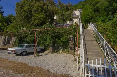 a car parked in a gravel lot next to a building at Do Re Mi Apartments in Budva