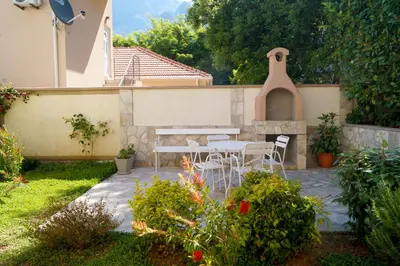a patio with a table and chairs in a garden at Veron Apartments in Kotor
