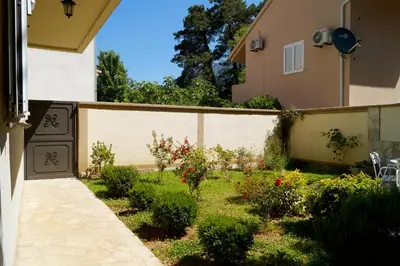 a garden in front of a house with a fence at Veron Apartments in Kotor