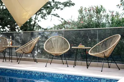 three chairs and a table next to a pool at Resort Stikovic in Dobra Voda