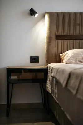 a bed with a nightstand with a clock on it at Resort Stikovic in Dobra Voda