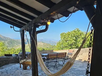 a porch with a hammock and a table and bench at Dembelija Rooms in Virpazar