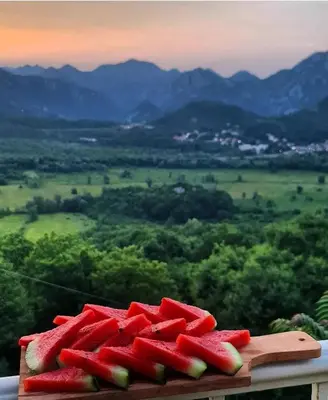 a plate of watermelon on a table with a view at Dembelija Rooms in Virpazar