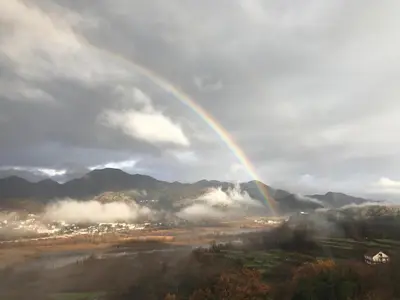 a rainbow in the sky over a field with a city at Dembelija Rooms in Virpazar