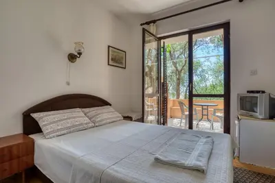 a bedroom with a bed and a balcony with a table at Guest House Vukovic in Petrovac na Moru