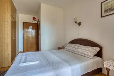 a bedroom with a large bed with a wooden headboard at Guest House Vukovic in Petrovac na Moru