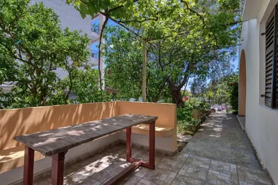 a wooden bench sitting on the side of a building at Guest House Vukovic in Petrovac na Moru