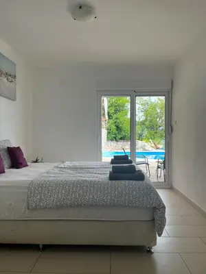 a white bedroom with a bed and a large window at Apartments Bonaca in Budva