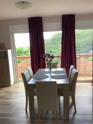 a dining room with a table and chairs and a window at Apartments Bonaca in Budva