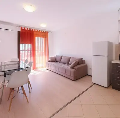 a living room with a couch and a table and a refrigerator at Apartment Adrialux in Budva