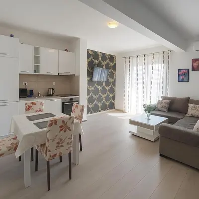 a kitchen and living room with a table and a couch at Apartment Adrialux in Budva