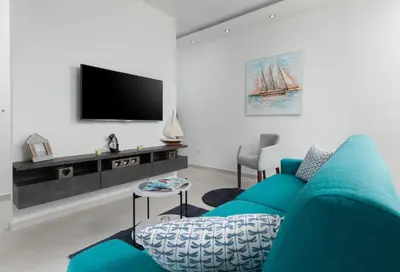a living room with a blue couch and a tv at Tramonto Apartments in Radanovići