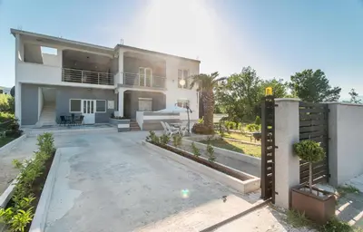 a house with a driveway and a fence at Tramonto Apartments in Radanovići