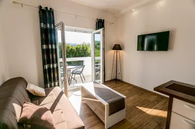 a living room with a couch and a television at Tramonto Apartments in Radanovići