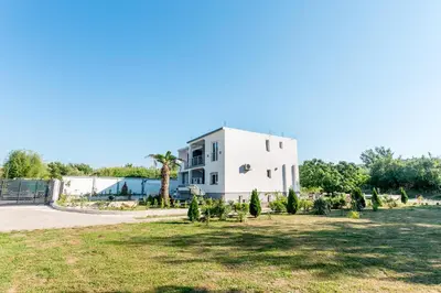 a white house with a yard in front of it at Tramonto Apartments in Radanovići
